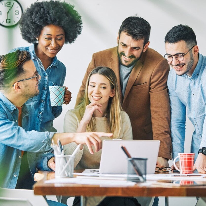 A group of coworkers looking at a laptop